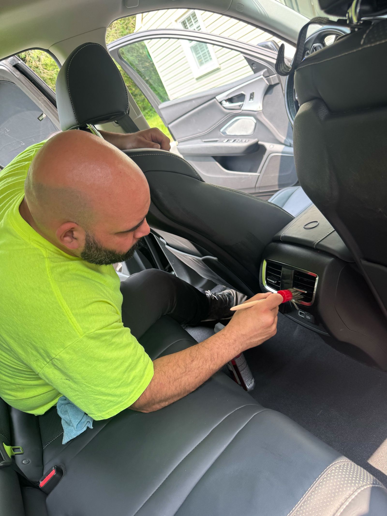 David Albaladejo cleaning the rear air vents of a car with a detailing brush