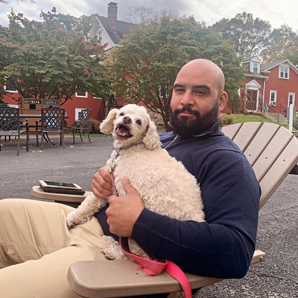 David Albaladejo, owner of Starshine Auto Detailing, sitting outdoors with his dog